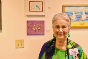 Abbie smiles as she stands in front of a wall of framed art