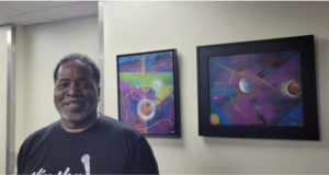 Chris stands in front of his art on display at the Austin Airport