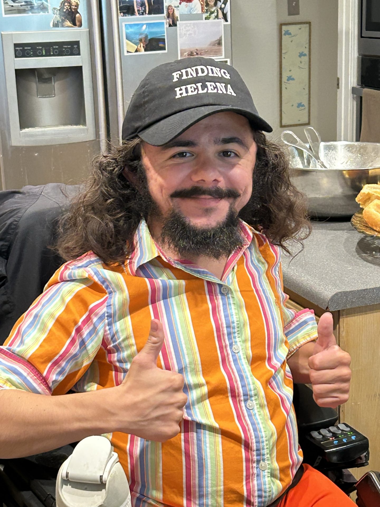 Kurt Wilkinson holding his thumbs up and wearing a hat that reads, "Finding Helena."